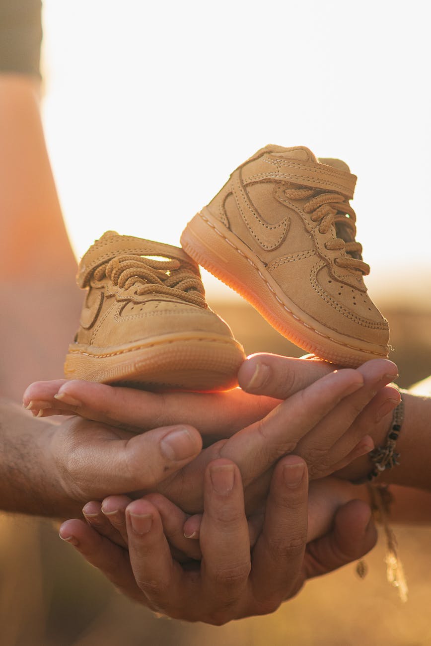 couple holding kids shoes on their hands