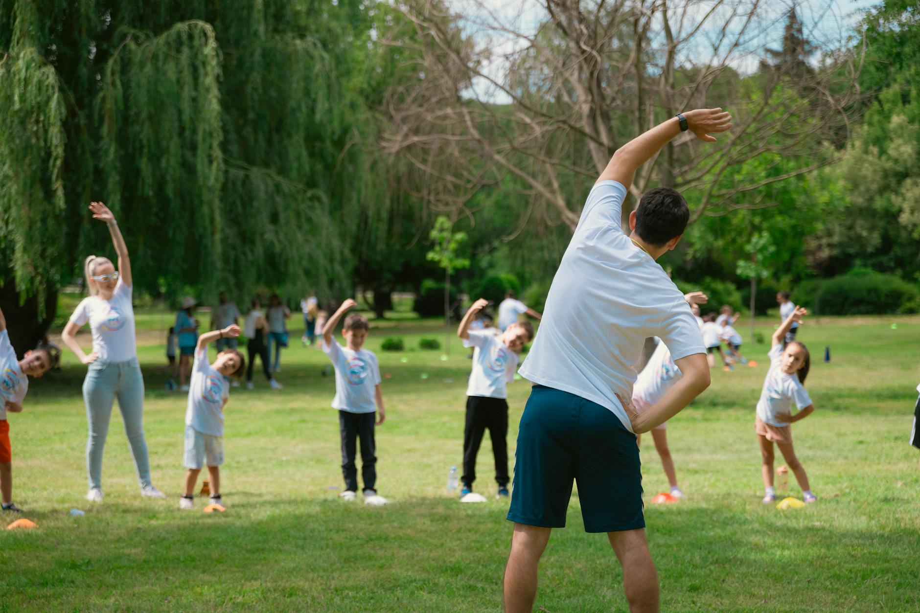 schoolchildren stretching on grass during an outdoor physical education class