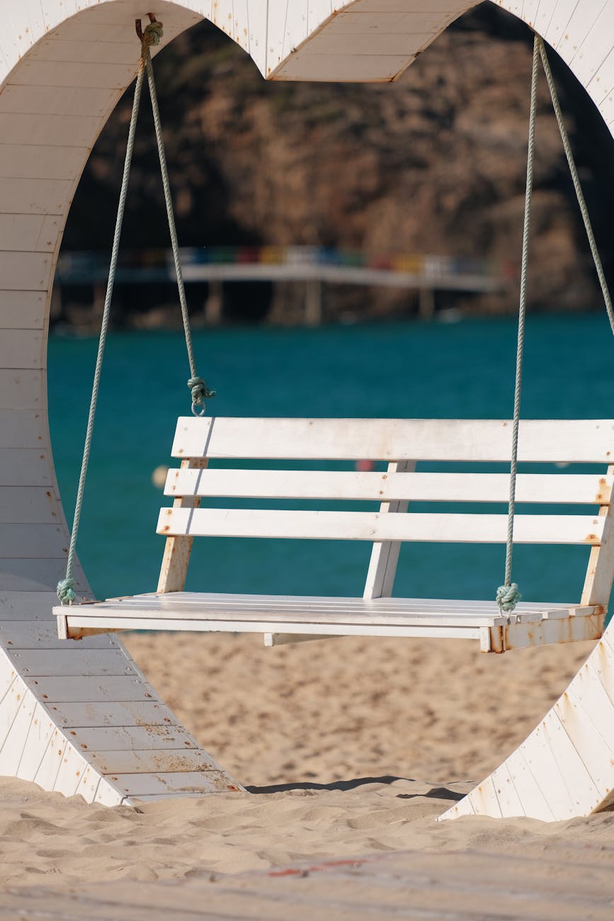 white swing on sandy beach with blue sea view