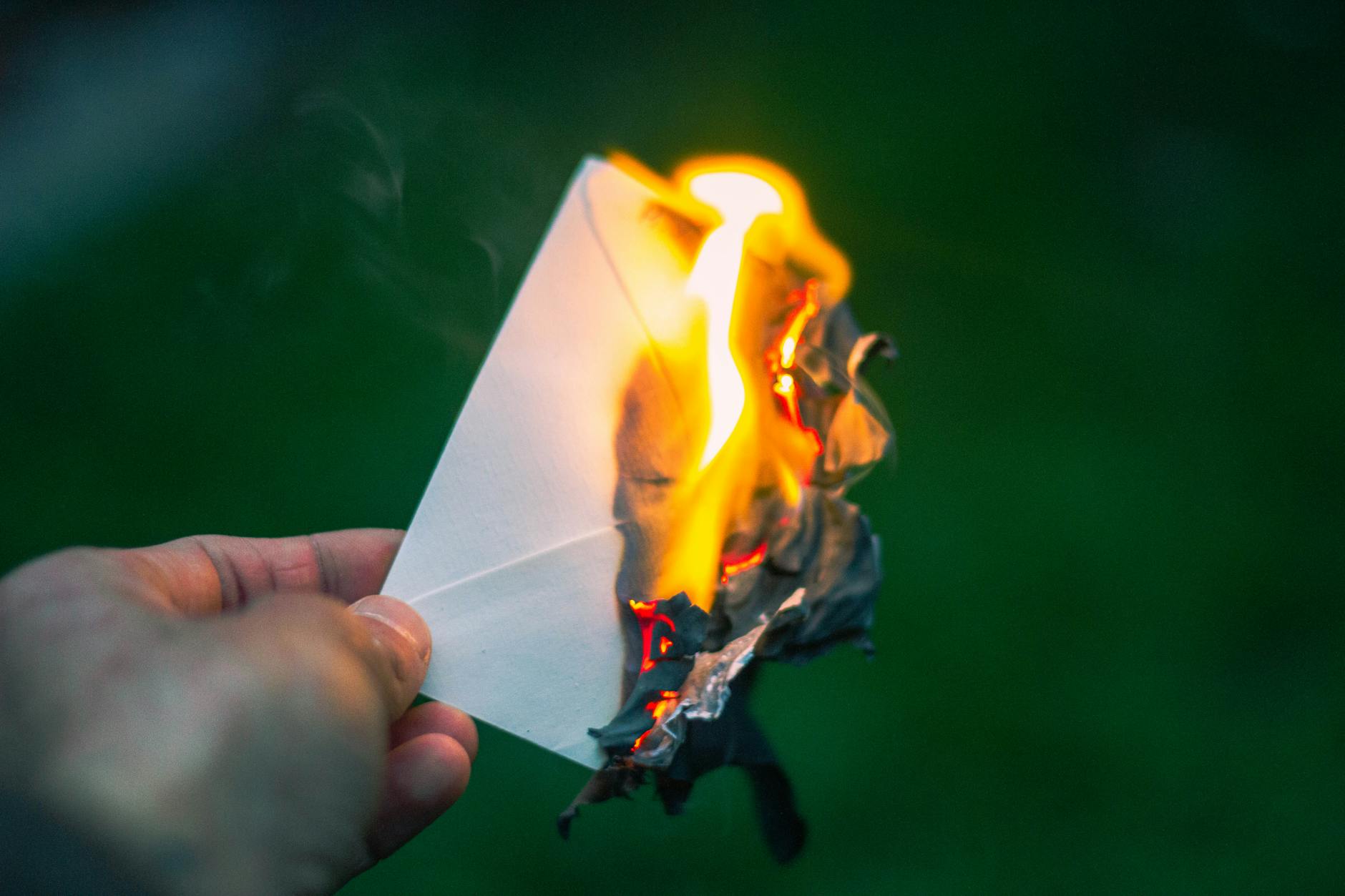 hand holding burning paper igniting in flames