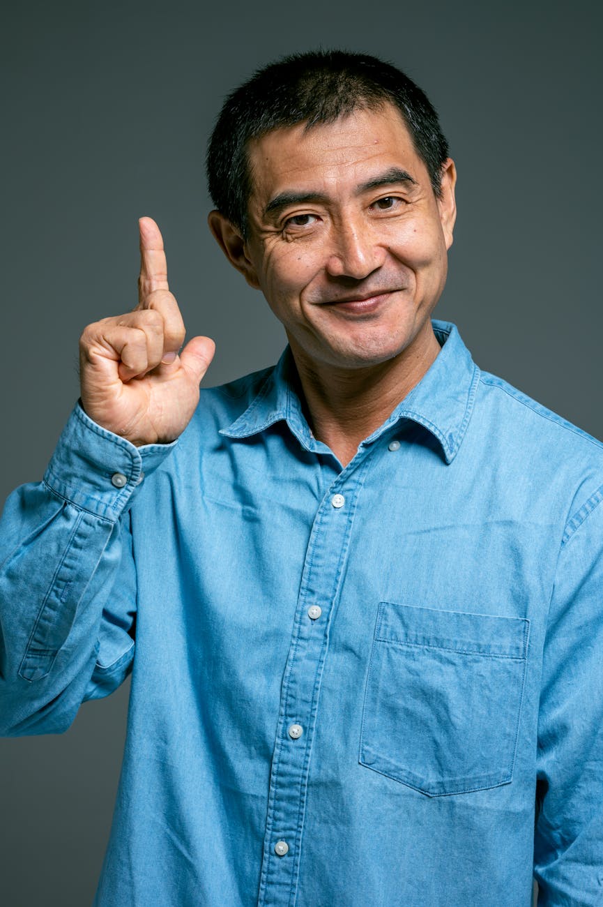 man in blue denim button up shirt with hand signal